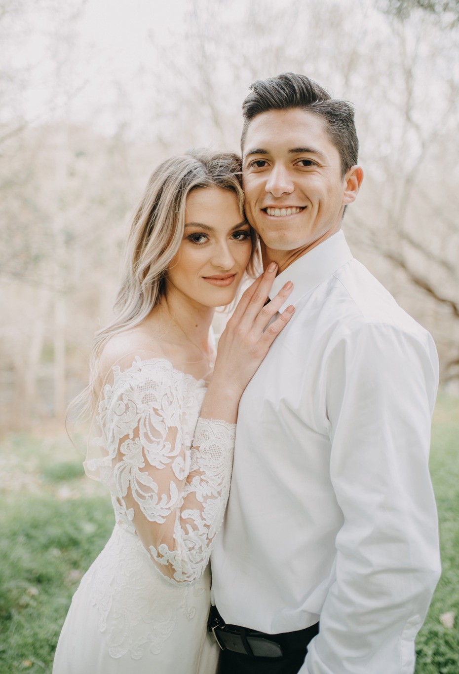 Happy couple in elegant wedding attire embracing outdoors