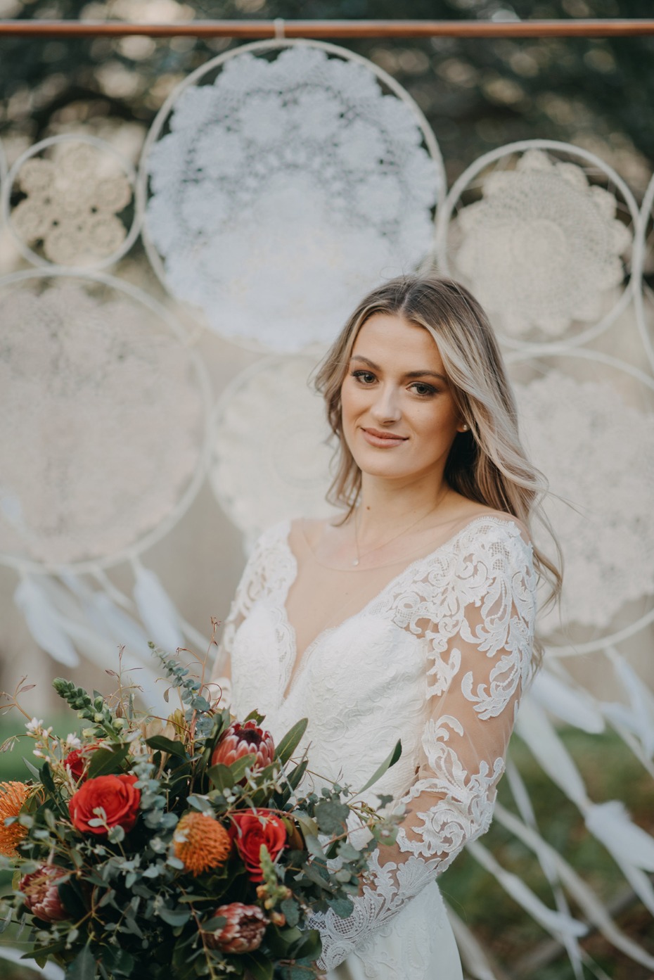 Bride in lace gown with bouquet at bohemian wedding