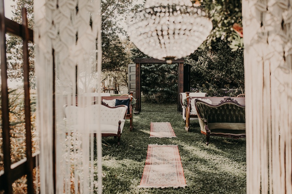 Outdoor wedding setup with vintage sofas and chandelier