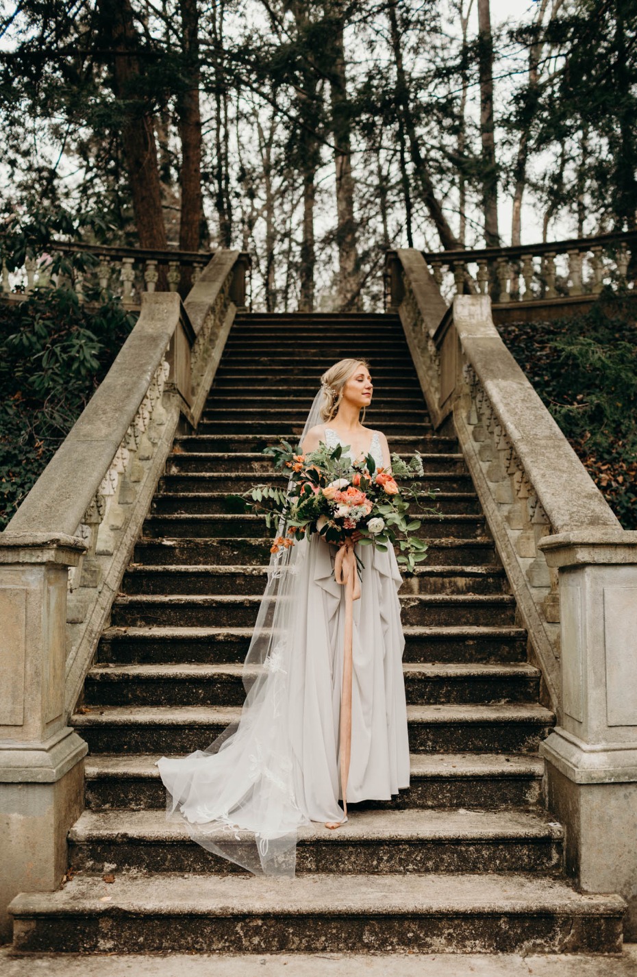 Bride with bouquet on stone stairs at wedding venue