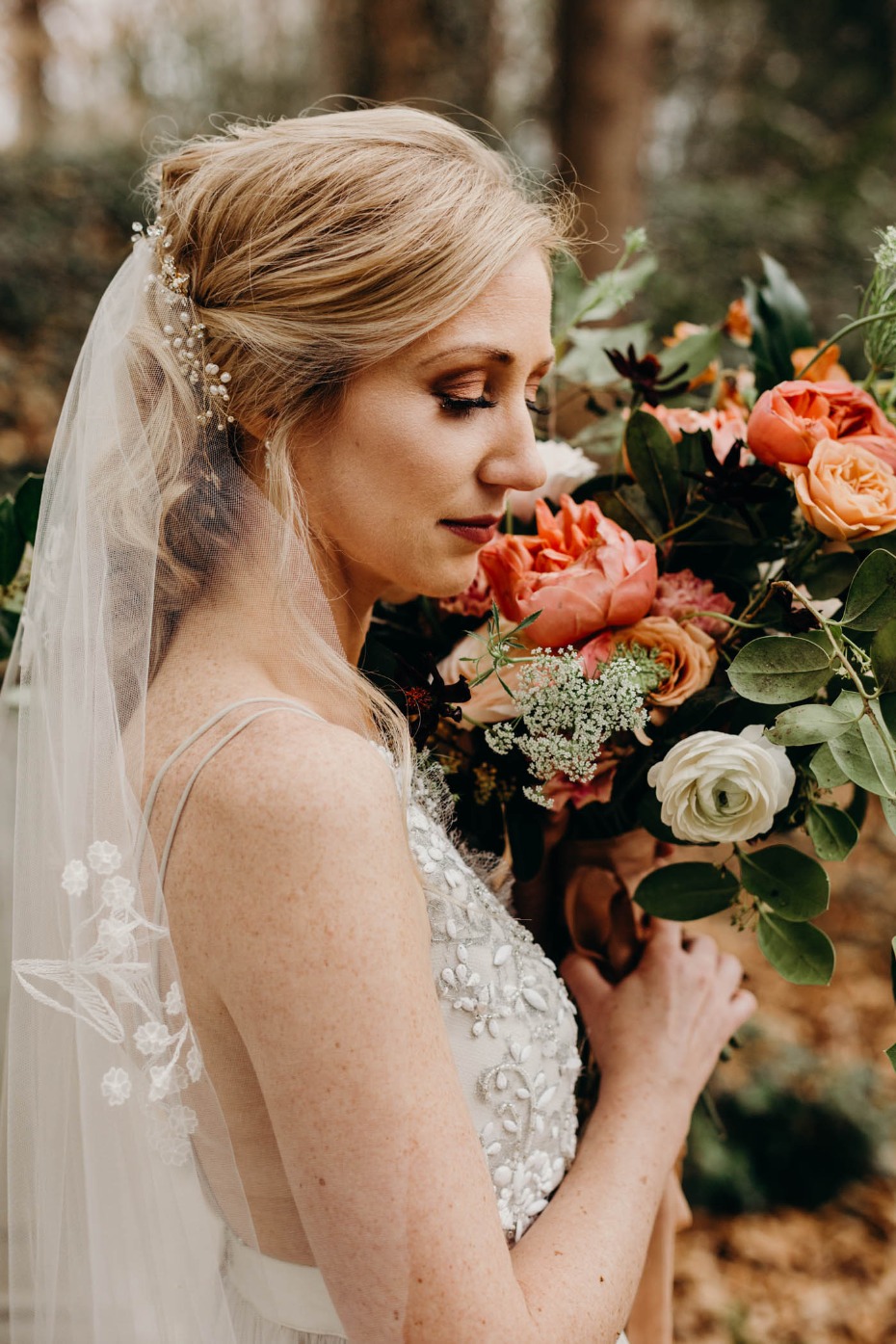 Elegant bride with bouquet wearing veil and beaded gown
