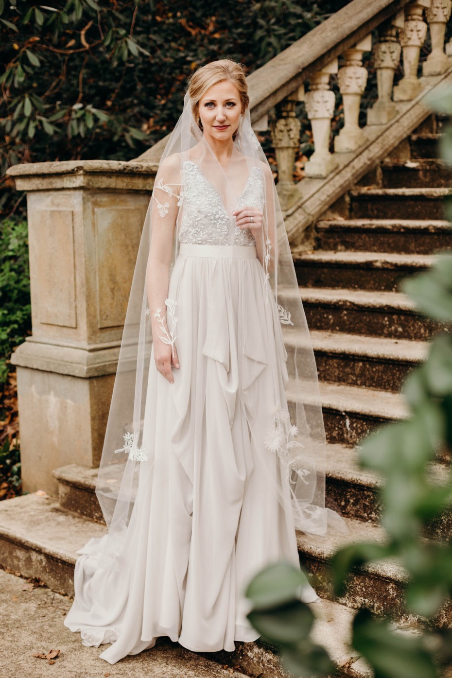 Bride in elegant, flowing wedding gown on stone steps