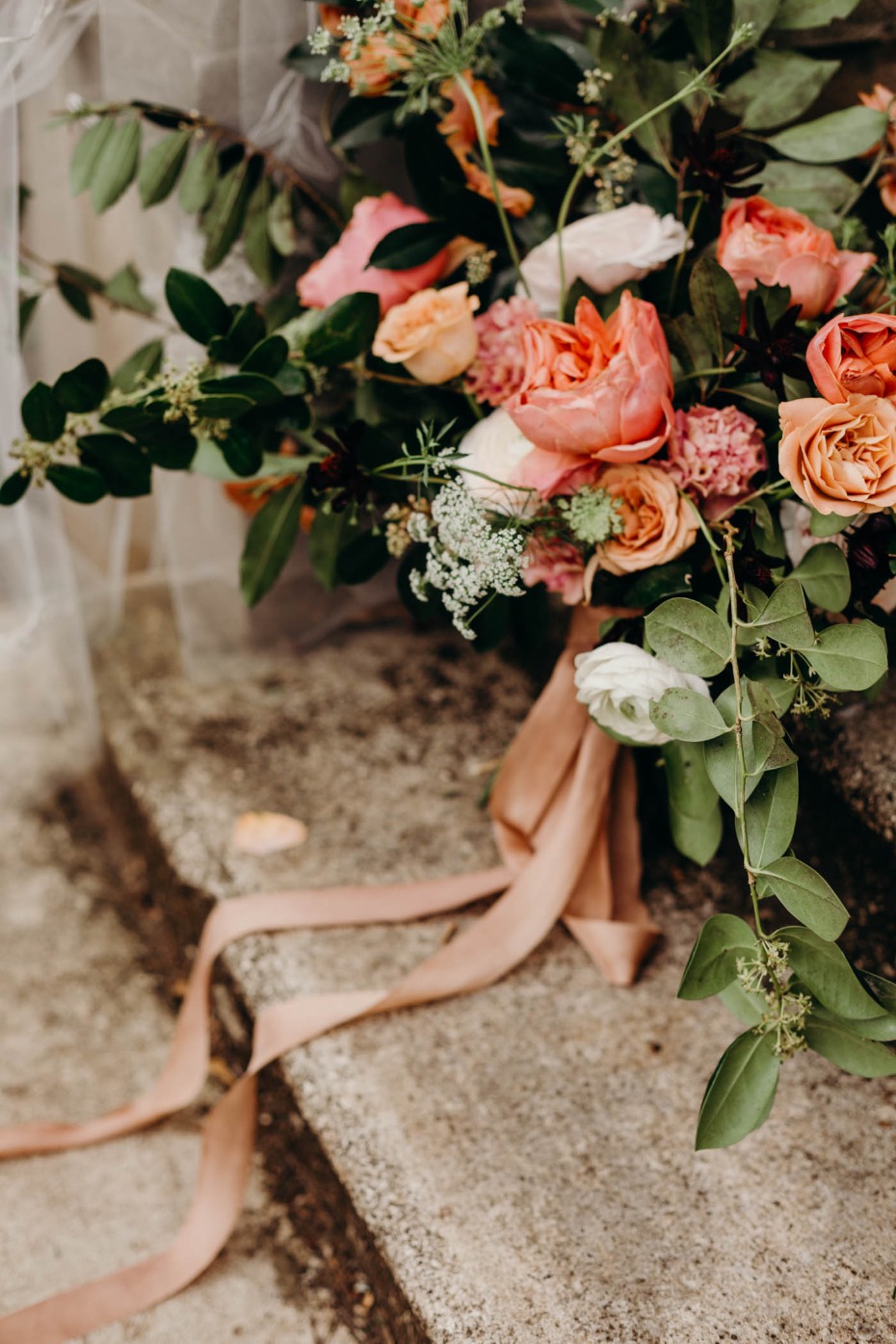 Elegant peach rose bouquet with flowing ribbon on stone