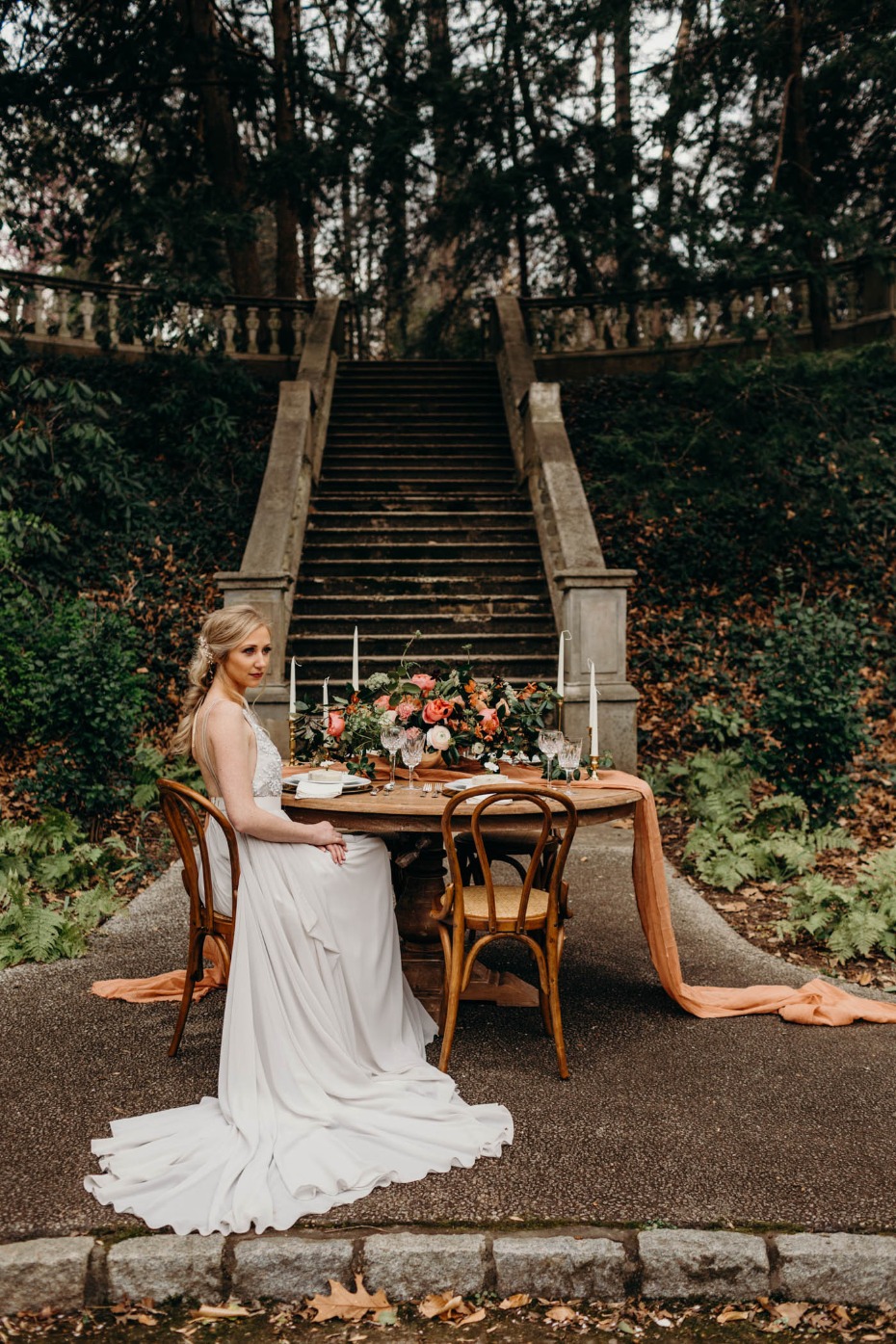 Bride in flowing gown at rustic outdoor wedding table