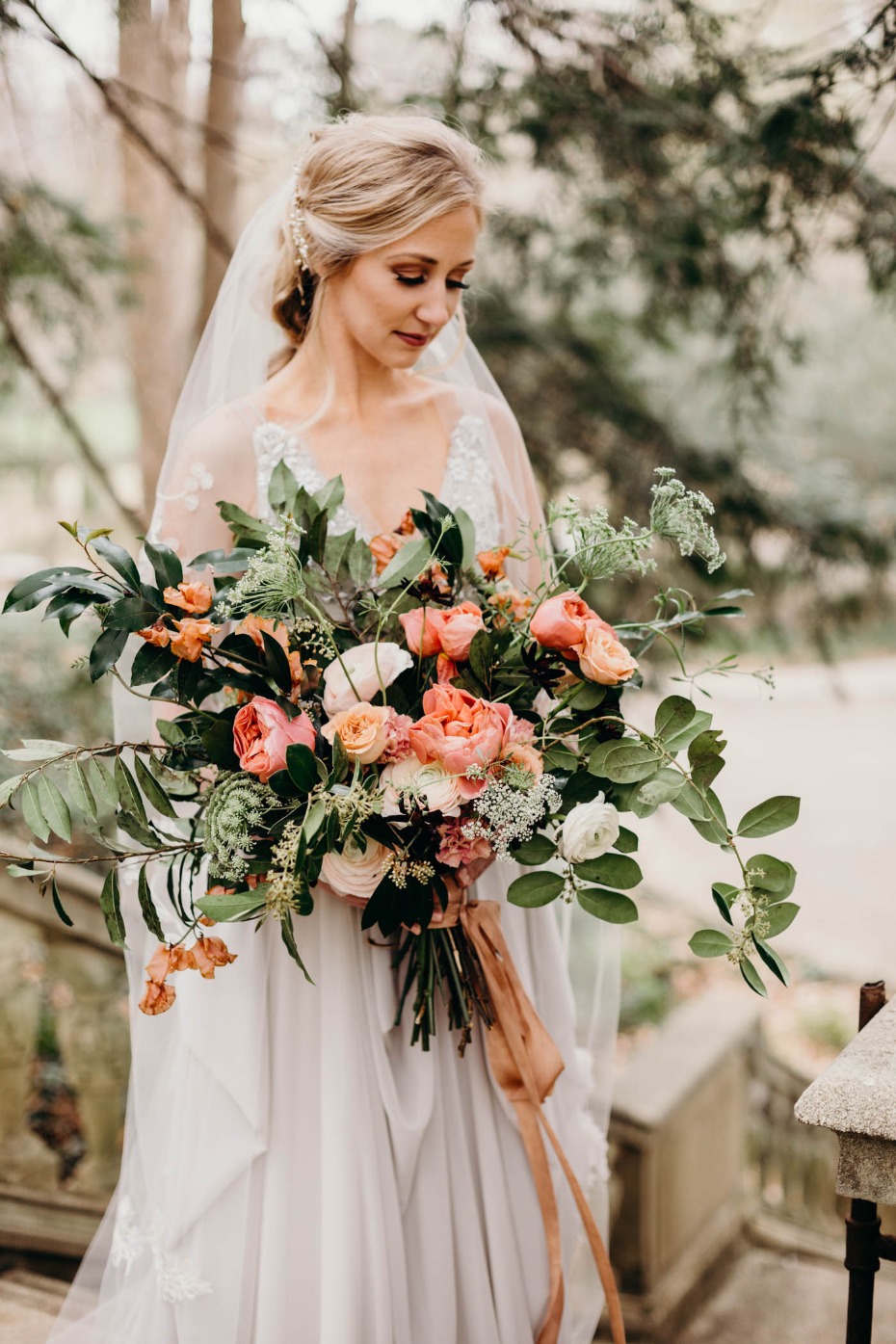 Blonde bride holding a lush coral and pink wedding bouquet