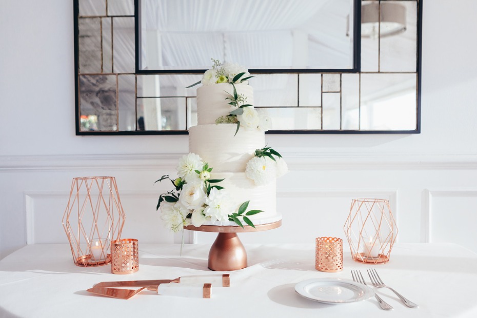 white wedding cake and copper cake stand
