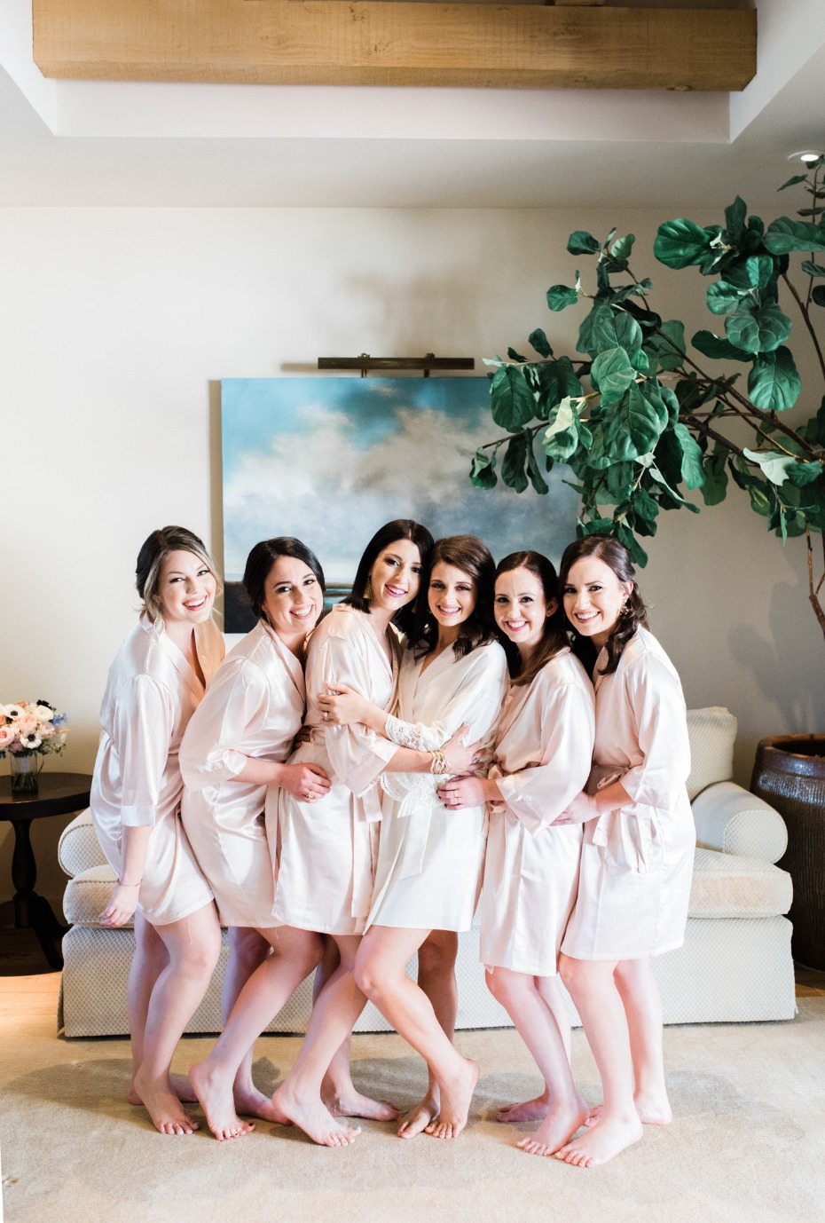 Bridesmaids in matching robes embracing before a wedding ceremony
