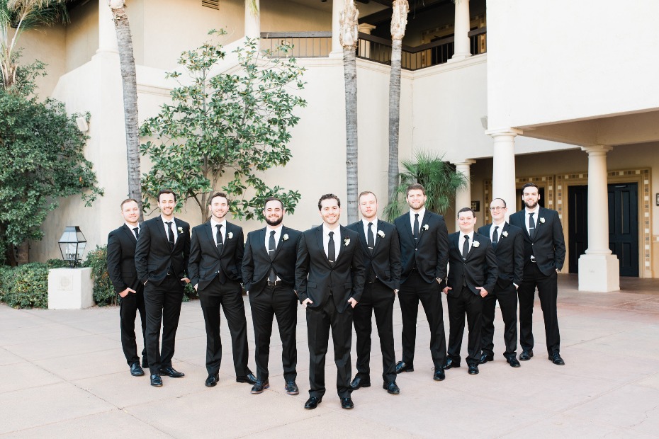 Groomsmen in black suits posing for a wedding day photo