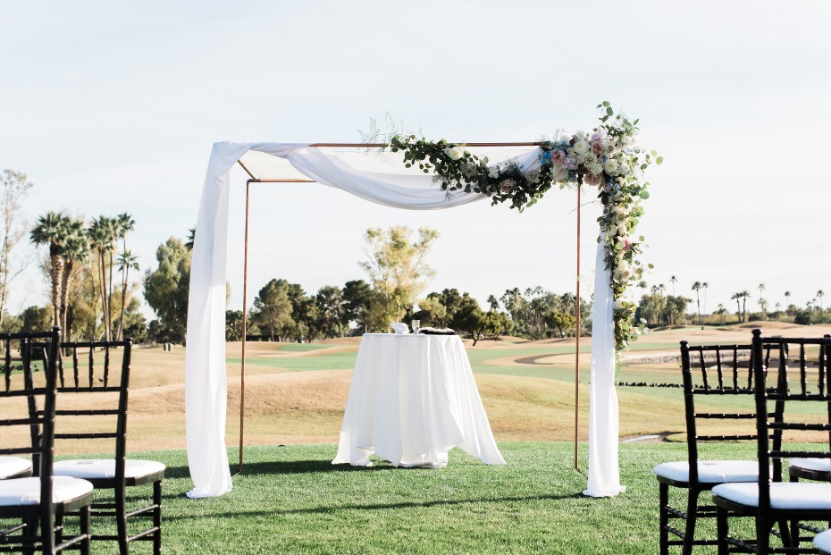 Outdoor wedding ceremony setup with floral arch and chairs