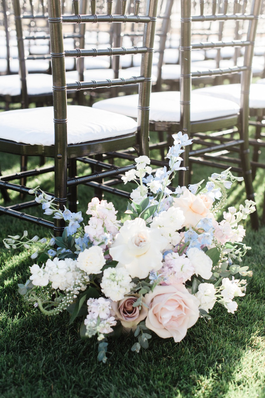 Wedding ceremony floral arrangement by chairs on grass