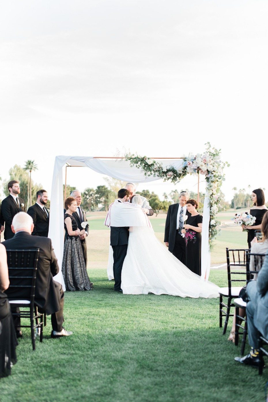 Elegant outdoor wedding ceremony with couple under a floral arch