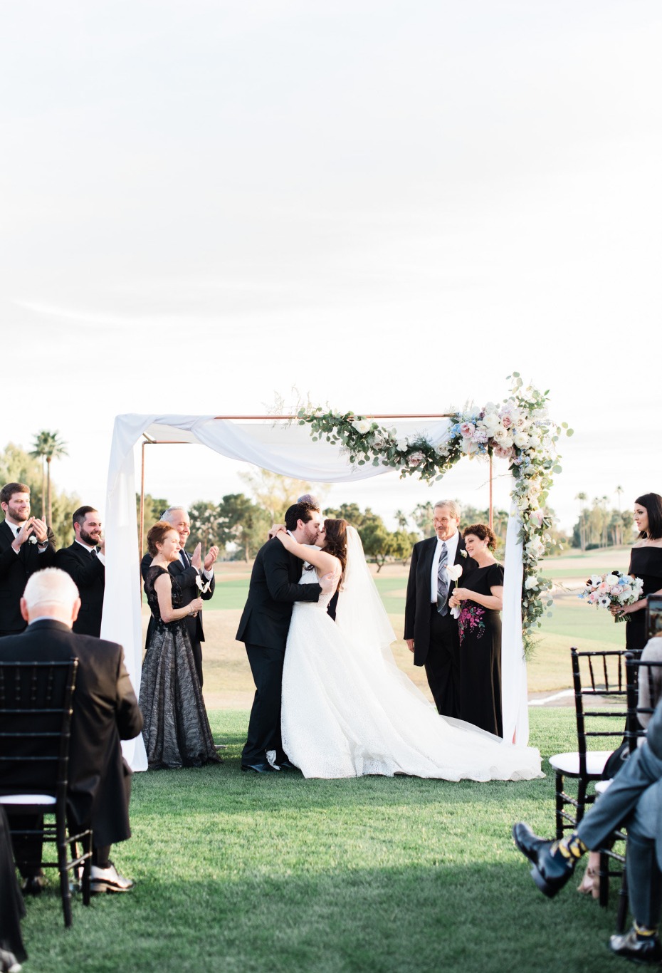 Bride and groom share a kiss during wedding ceremony outside