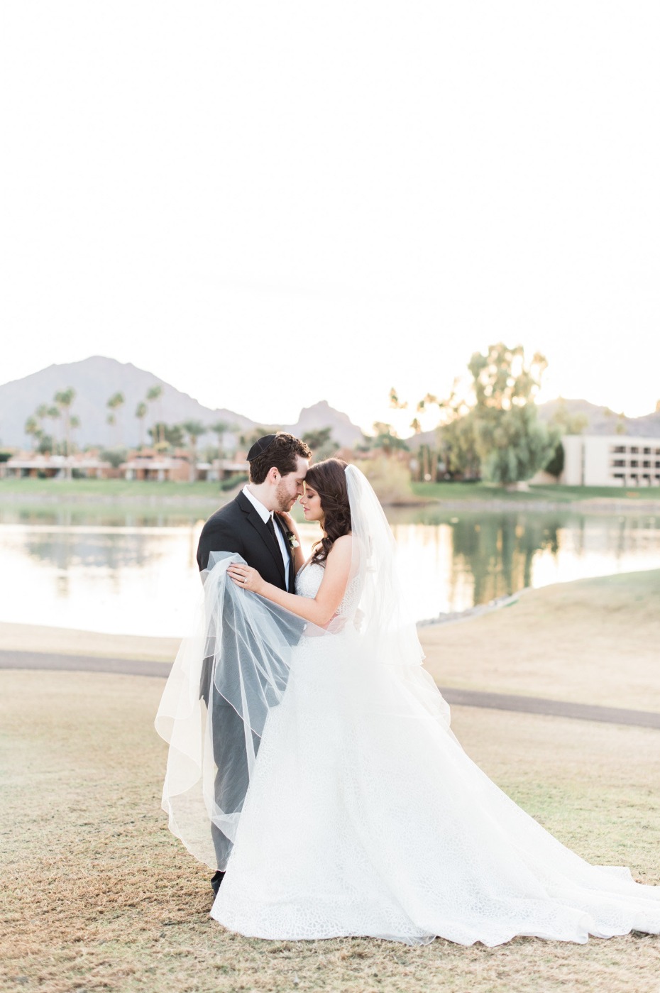 Loving couple in wedding attire pose on a scenic golf course