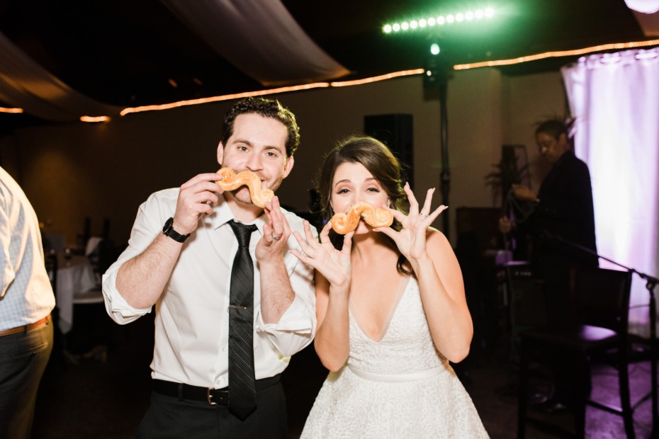 Happy newlyweds pose playfully with bread at their wedding