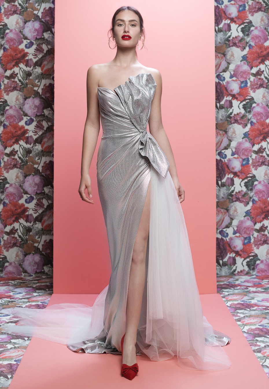 Woman in silver gown with red shoes and floral backdrop