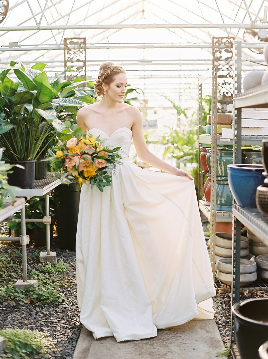 Bride in gown with bouquet at greenhouse wedding venue