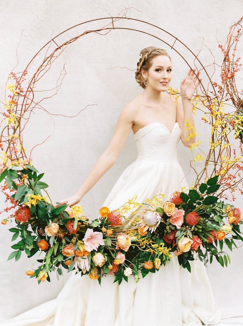 Bride in white dress with floral circle arch decoration