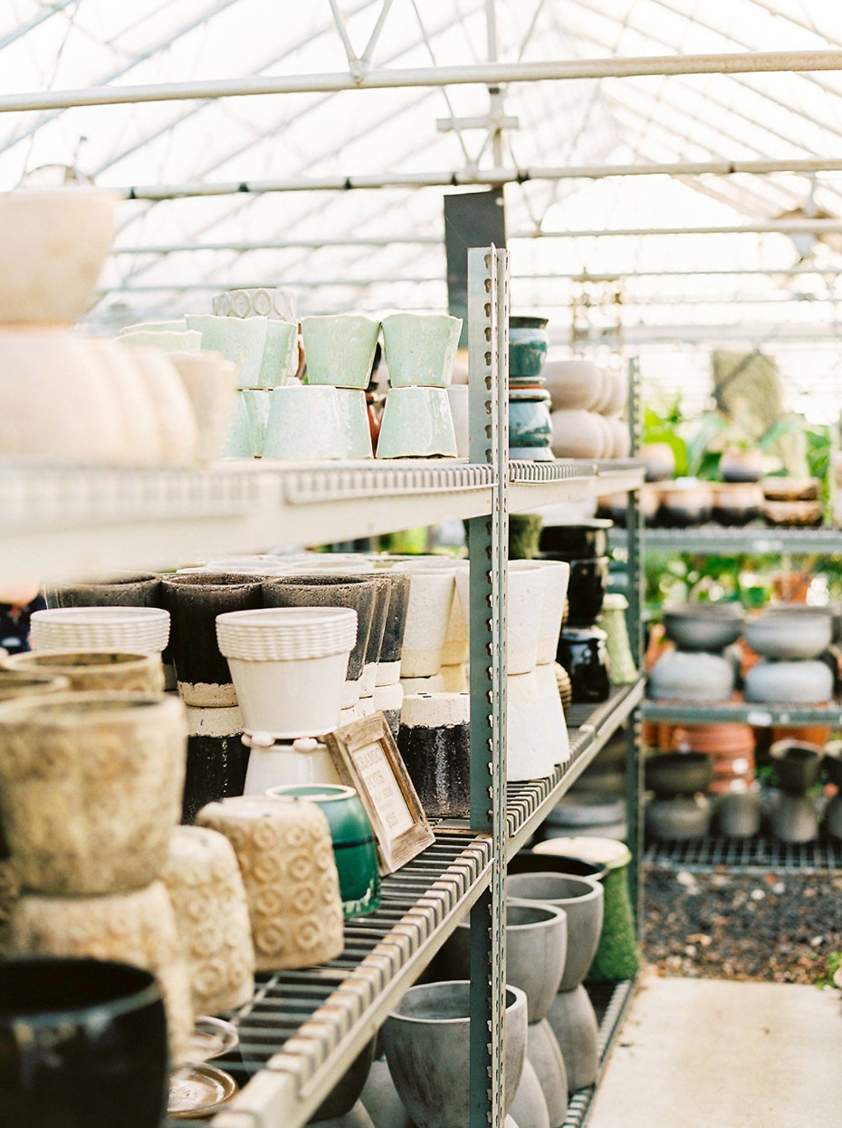 Assorted ceramic plant pots on shelves in greenhouse