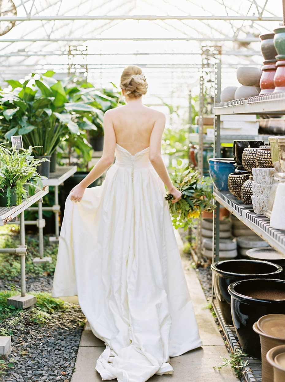 Bride in gown walks through lush greenhouse plants