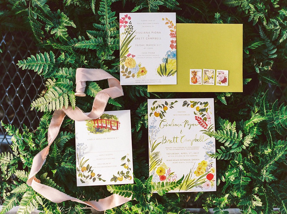 Floral wedding invitations on ferns with ribbon and stamps