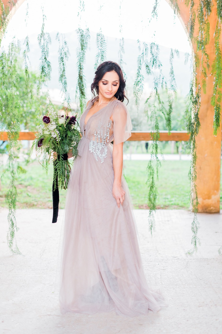 Bride in flowy gown holding bouquet outdoor wedding