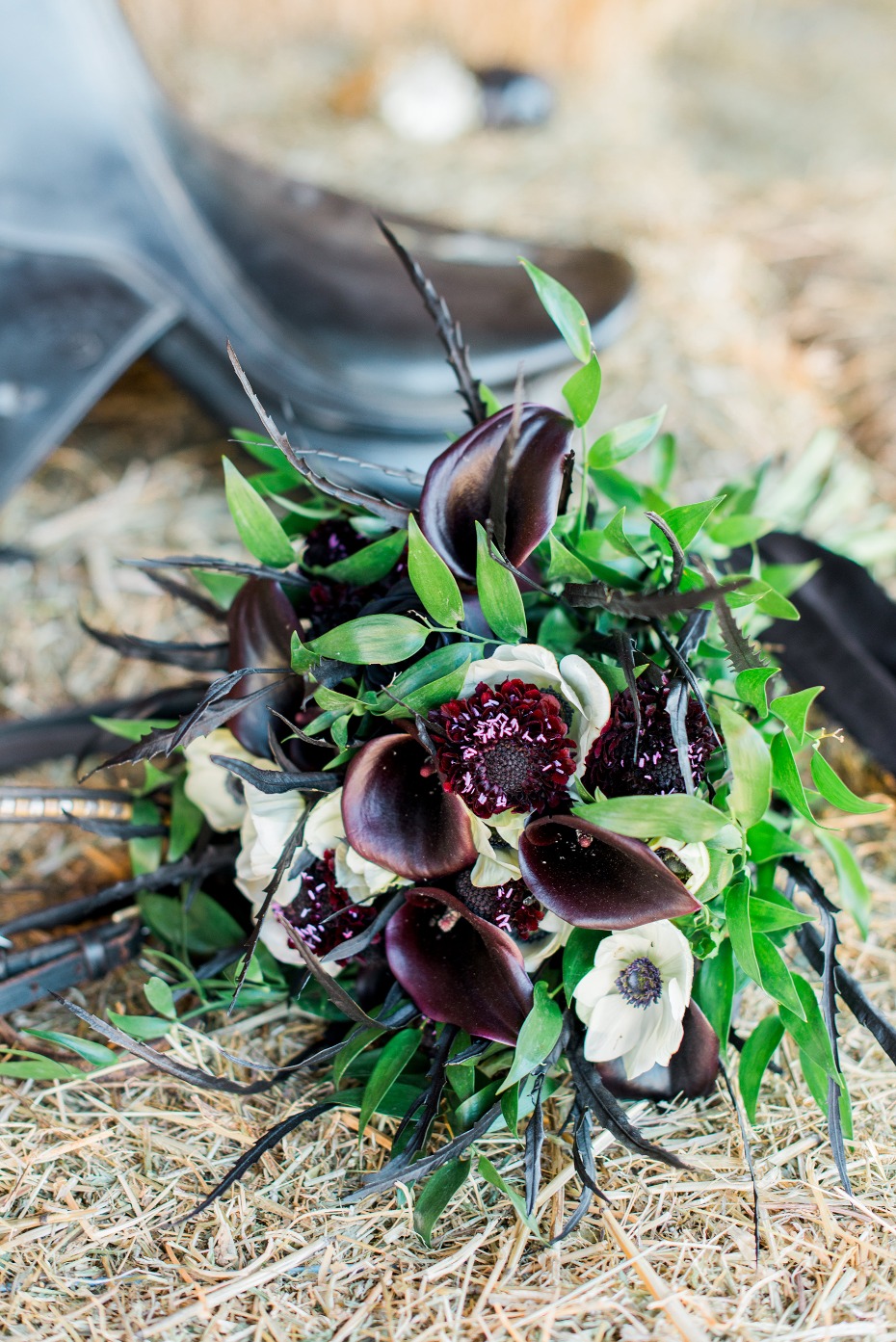 Dark and elegant wedding flower bouquet on hay bale