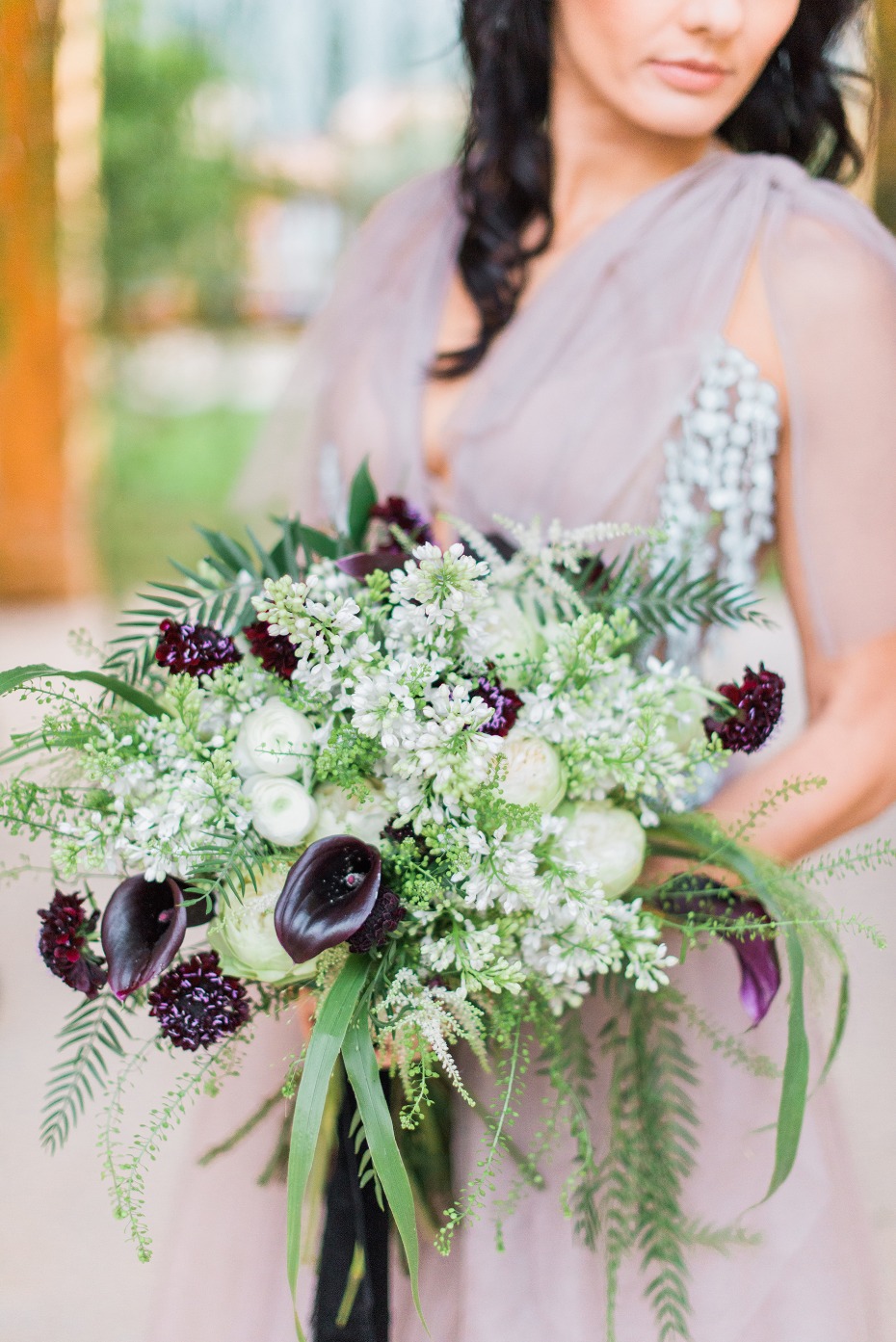 Bride holds a bouquet of calla lilies and white flowers
