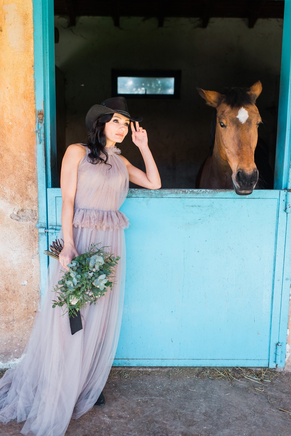 Woman in gown and horse in stable posing for portrait