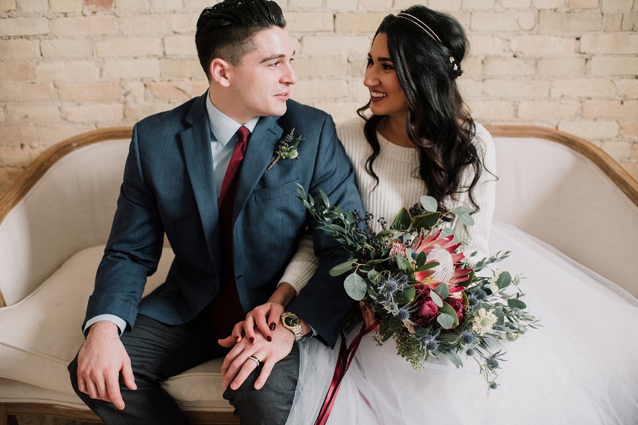 Elegant couple embraces on a white couch during a wedding shoot