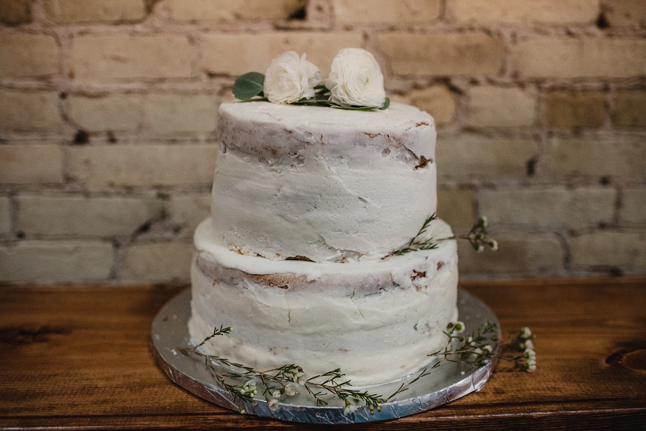 Rustic two-tiered wedding cake with flowers on a wooden table