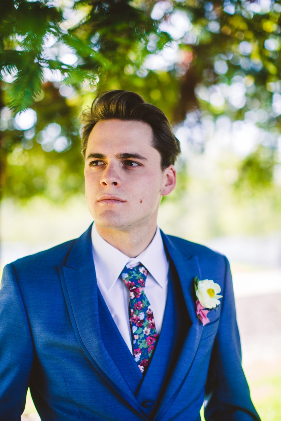 Groom in blue suit with floral tie looks off to the side