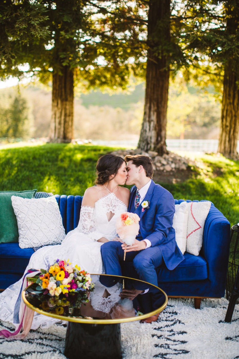 Bride and groom kissing on blue couch outdoors