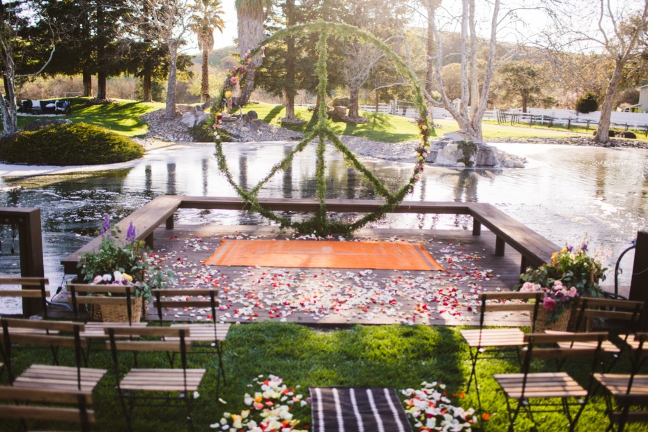 Outdoor wedding venue with a peace sign arch by a pond
