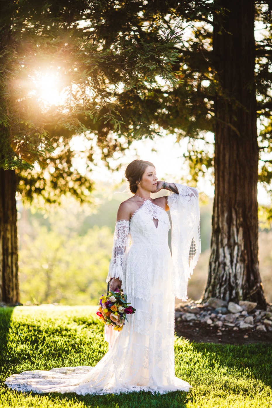 Bride in lace wedding dress in sunlit natural setting