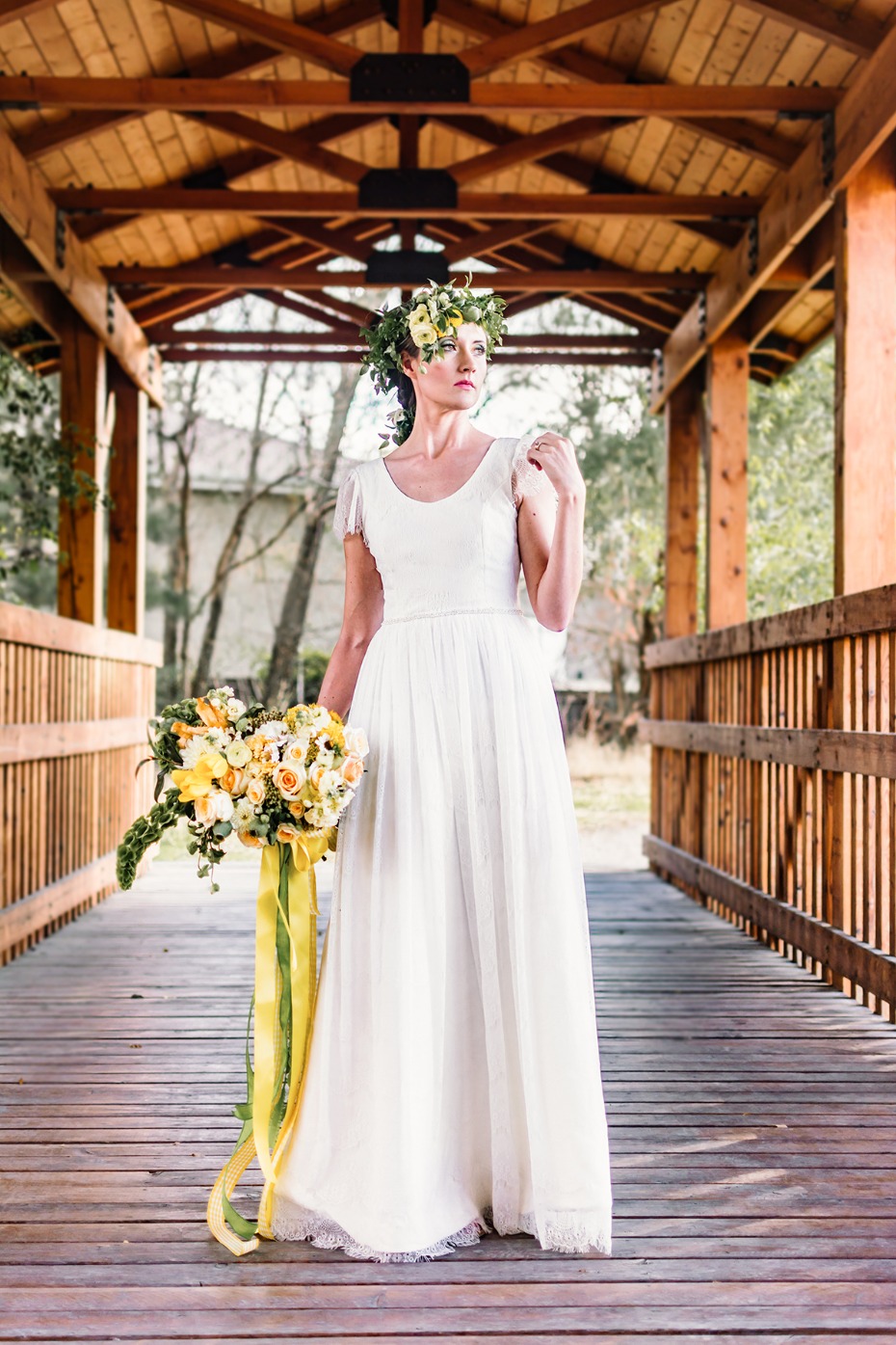 Bride with flower crown and bouquet on wooden bridge