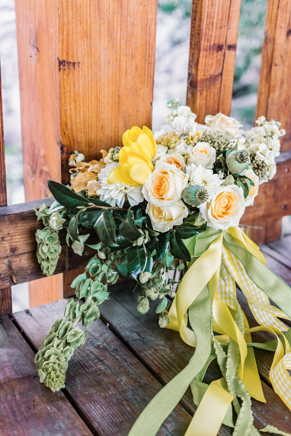 Yellow and white bouquet with ribbon on wooden bench