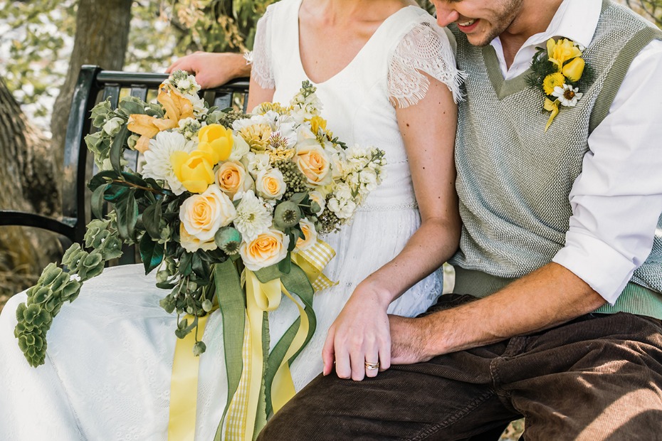 Bride and groom on bench with yellow wedding bouquet