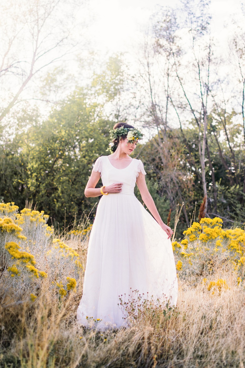 Bride in a white dress with a flower crown in a field