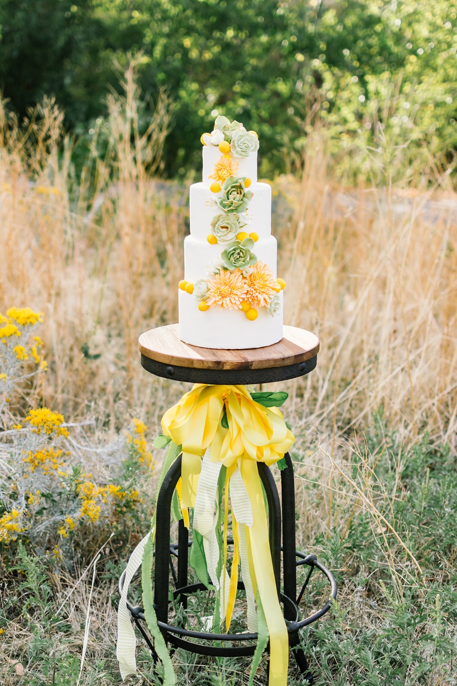 Elegant four tier wedding cake with floral decor outdoors
