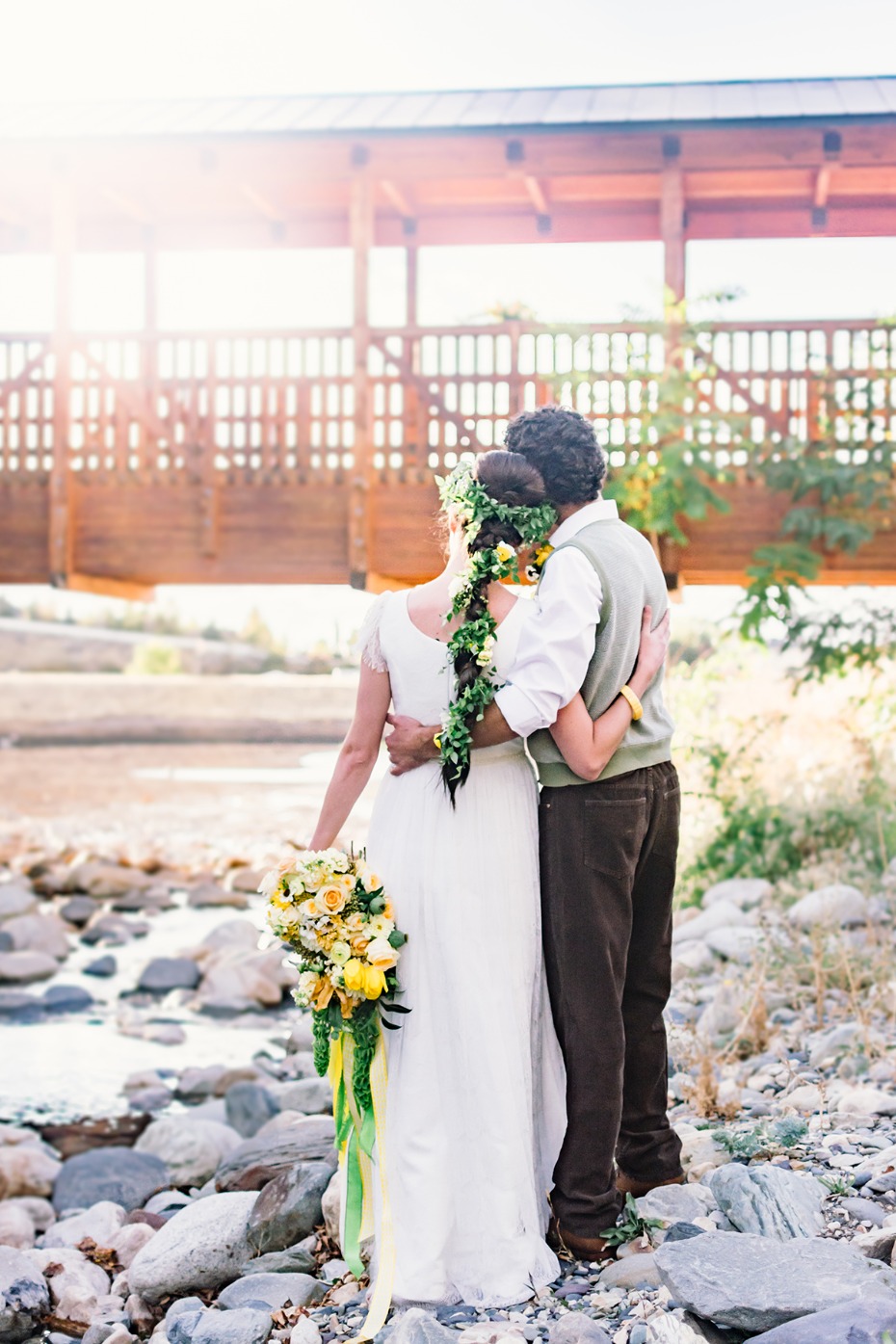 Newlyweds embrace by a stream on their wedding day