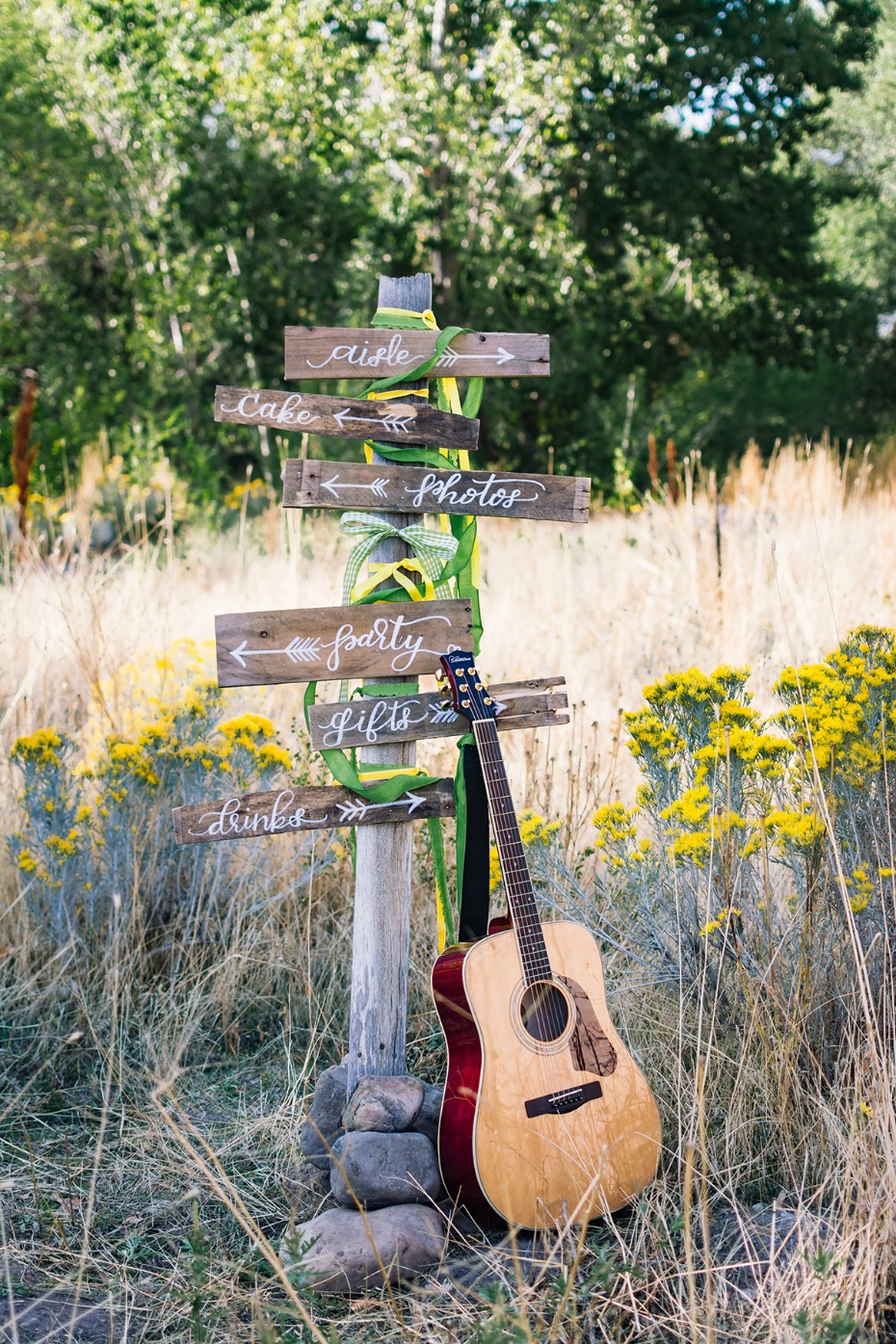 Rustic wedding sign with guitar pointing to the party