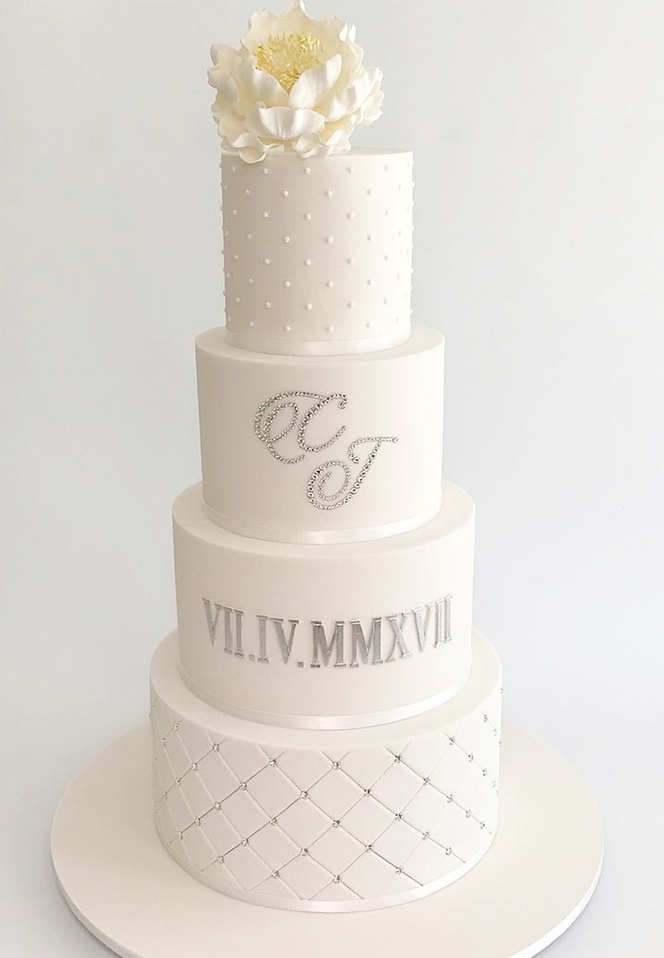 white and silver wedding cake with wedding date in roman numerals