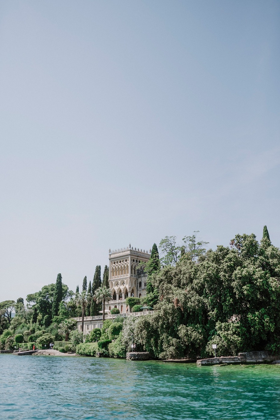 Lake view of an ornate building surrounded by lush trees