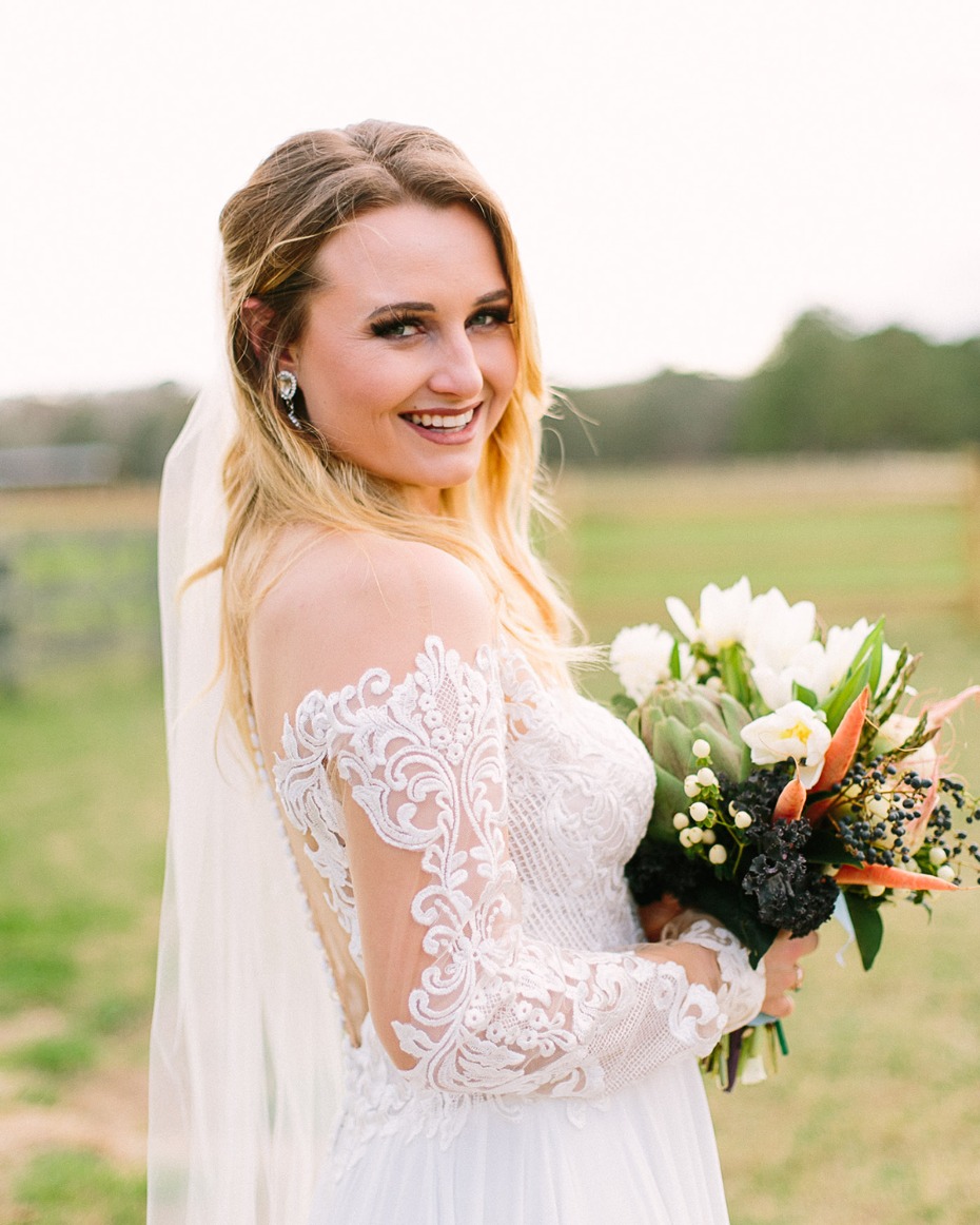 Blonde bride in lace dress holding wedding bouquet