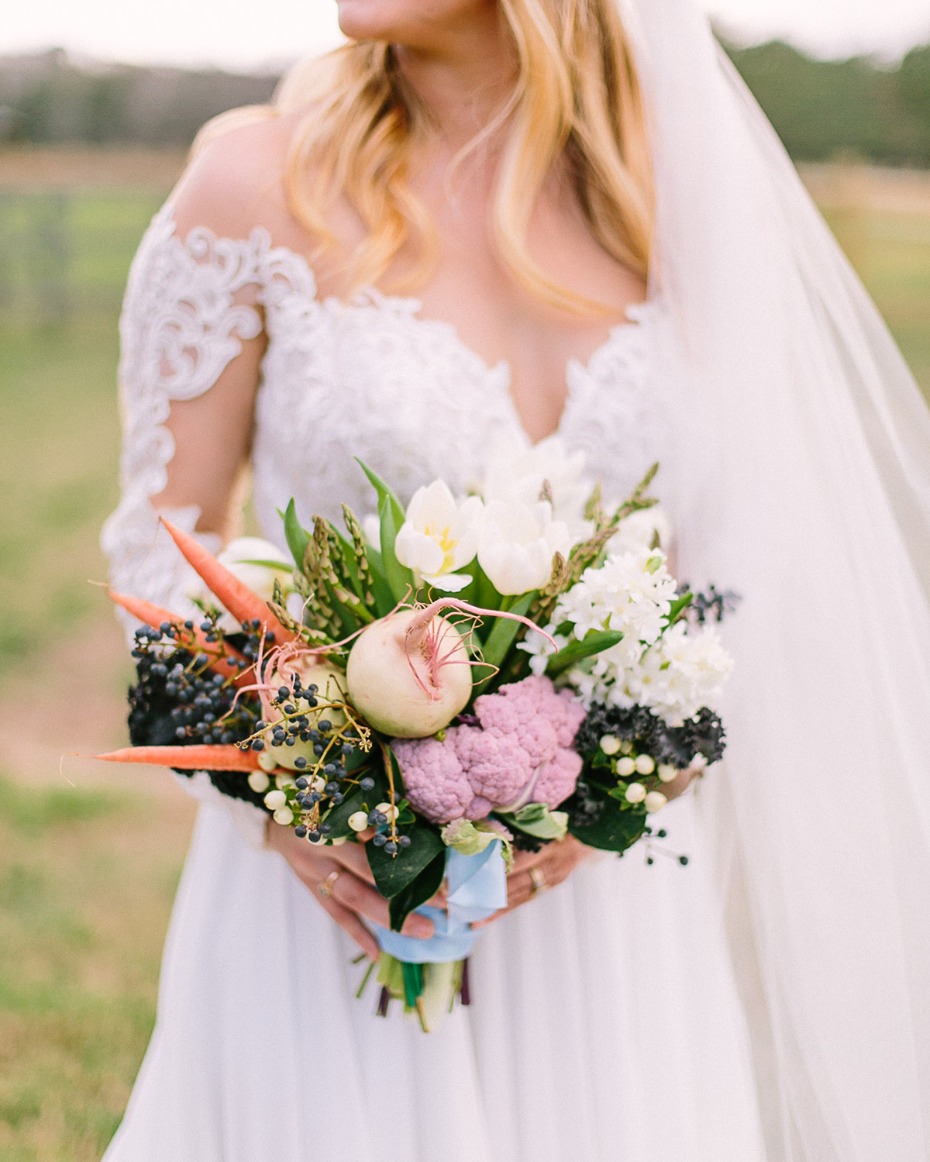 Bride in lace gown holds vegetable wedding bouquet