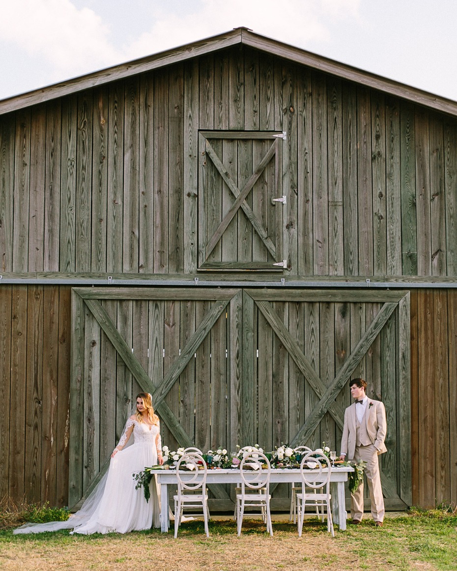 Bride and groom by table at rustic barn wedding venue