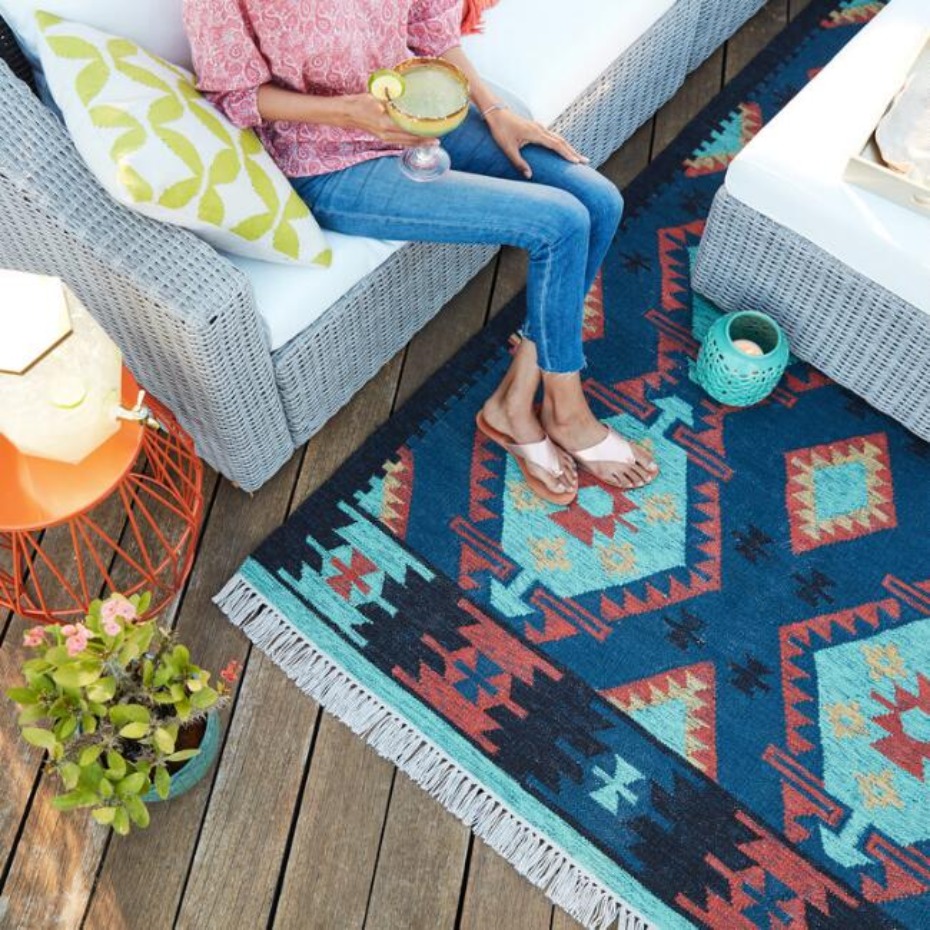 Woman enjoying patio with patterned rug and cocktail