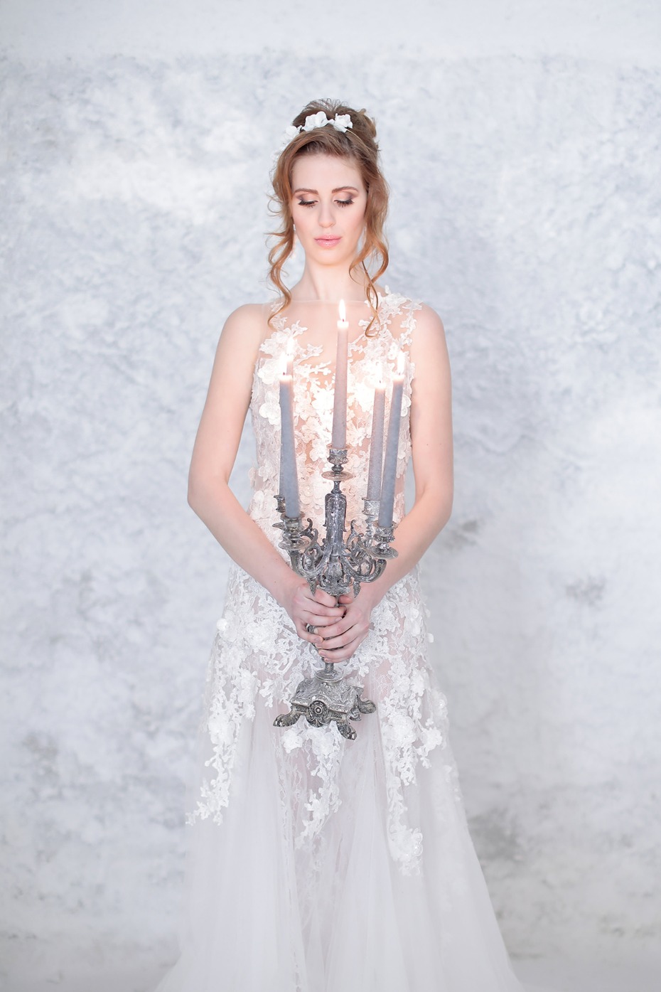 Bride in white dress holding candelabra with candles