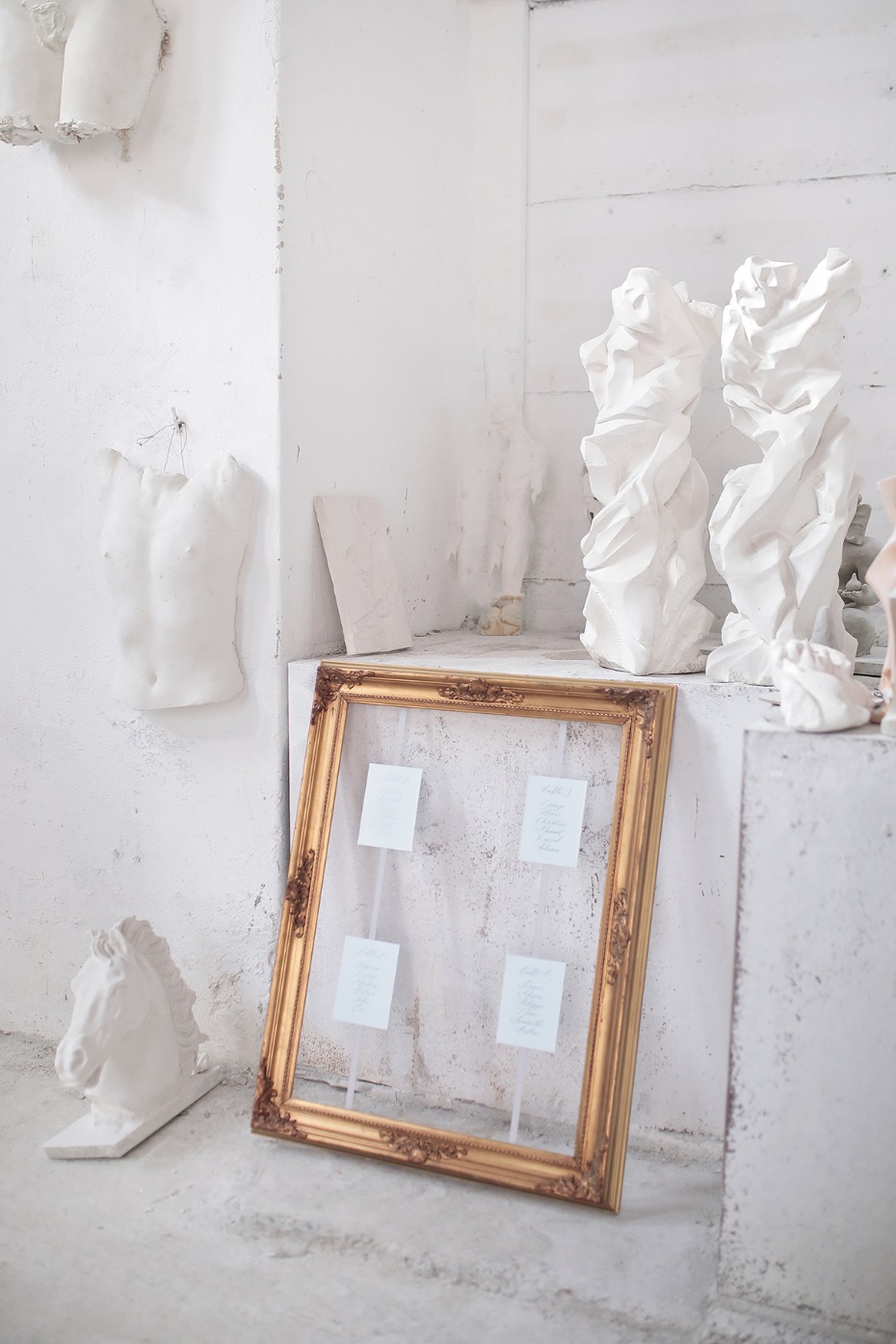 Gold framed table cards with white sculptures in the background