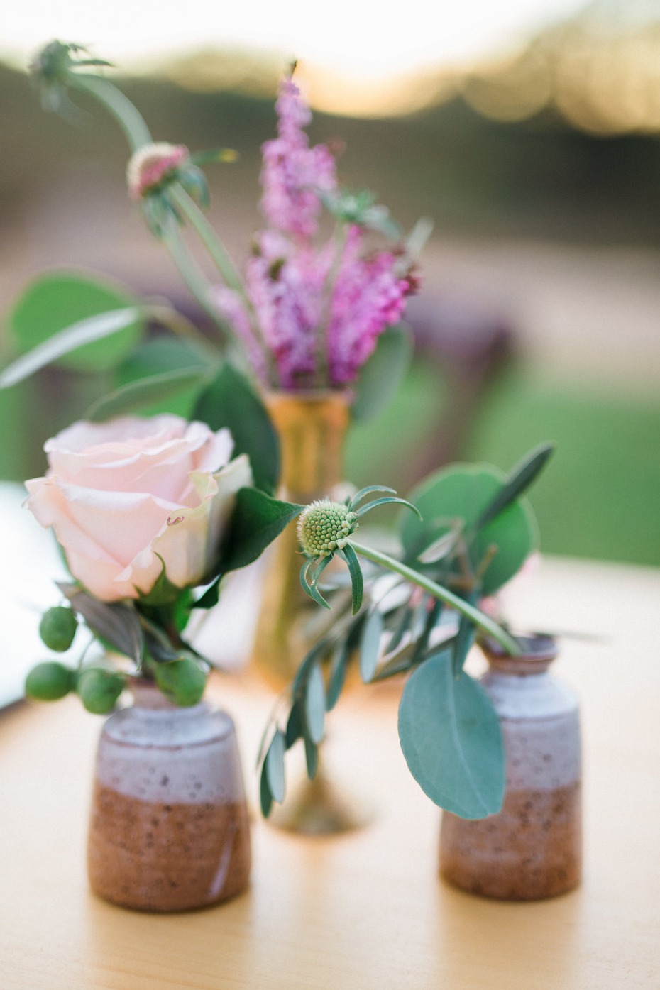 Rose and purple wildflower arrangements in rustic vases
